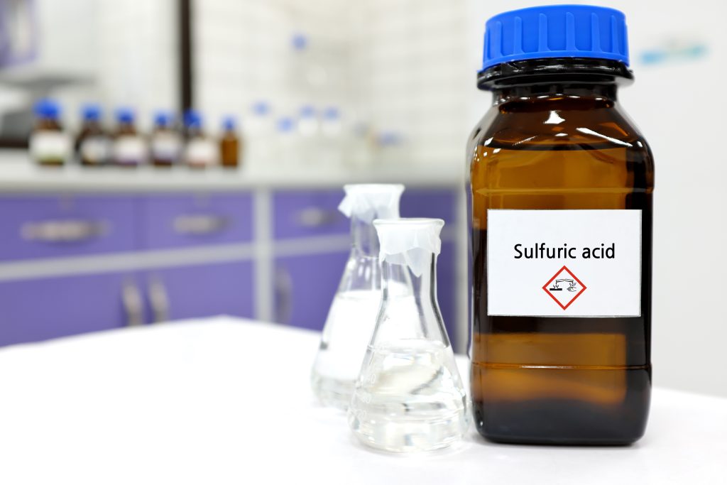 研究所内に配置されている硫酸、硫酸は化学物質保管専用の瓶の中にある。横に透明の液体（硫酸）が張っているフラスコ